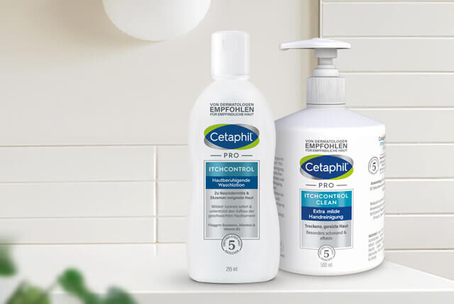 Die zwei Cetaphil Produkte Reinigungslotion und PRO ItchControl Hautberuhigende Waschlotion für die Körperreinigung von empfindlicher Haut, auf einem Badezimmerregal vor weißen Wandfliesen.